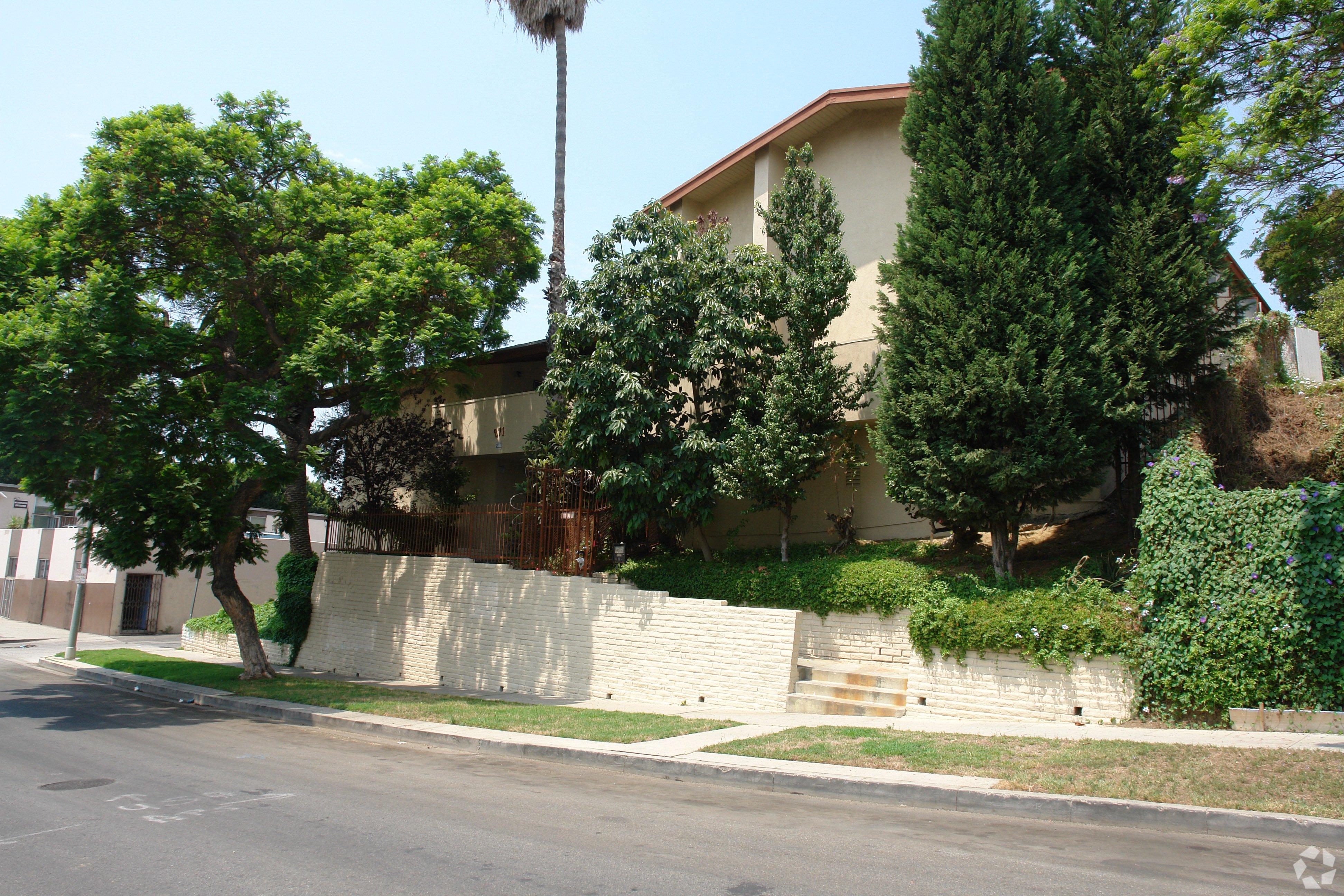 A house with a white fence and trees in front.